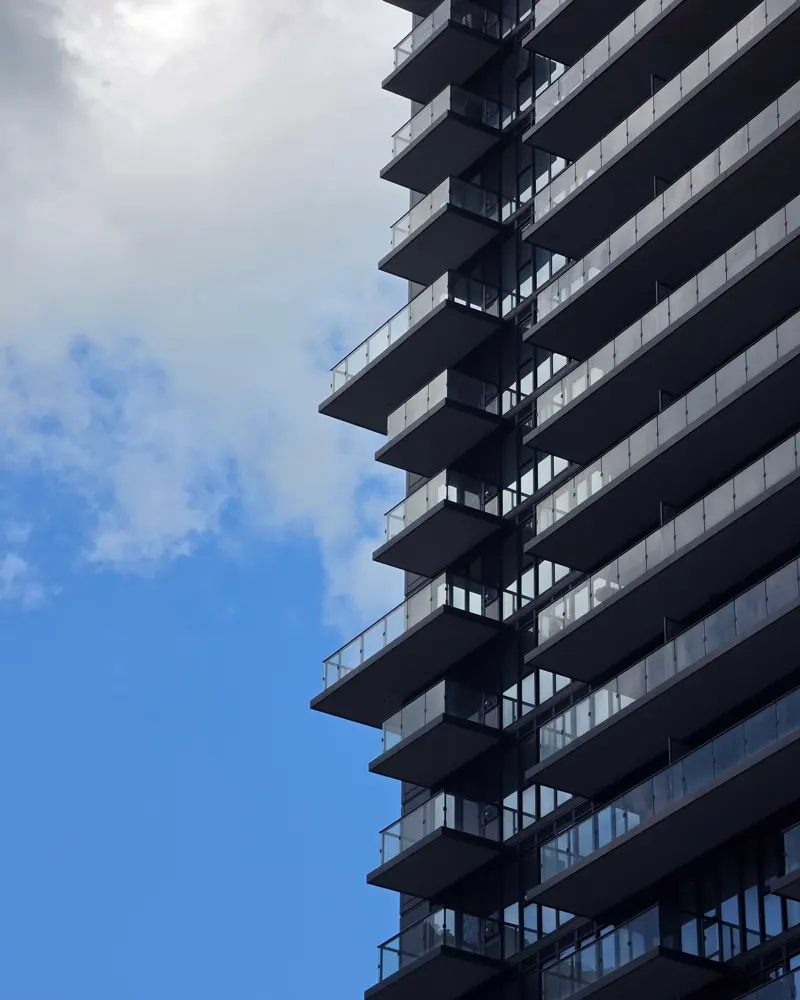 Varandas em balanço de um edifício residencial escuro, em ritmo repetido contra o céu.