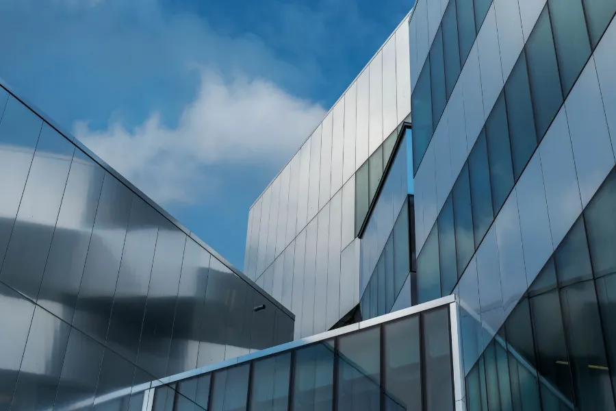 Fachada de arquitetura contemporânea, com planos angulares em vidro e metal contra o céu.